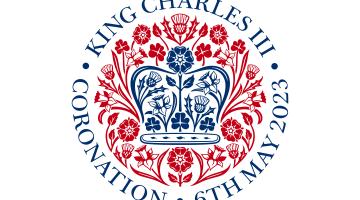 Official emblem of King Charles III's coronation, which is blue and red. There is a blue crown with flowers representing UK nations, surrounded by flowers and encircled by text saying 'King Charles III, Coronation, 6th May 2023